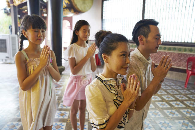 Young happy asian family praying in shrine — Stock Photo
