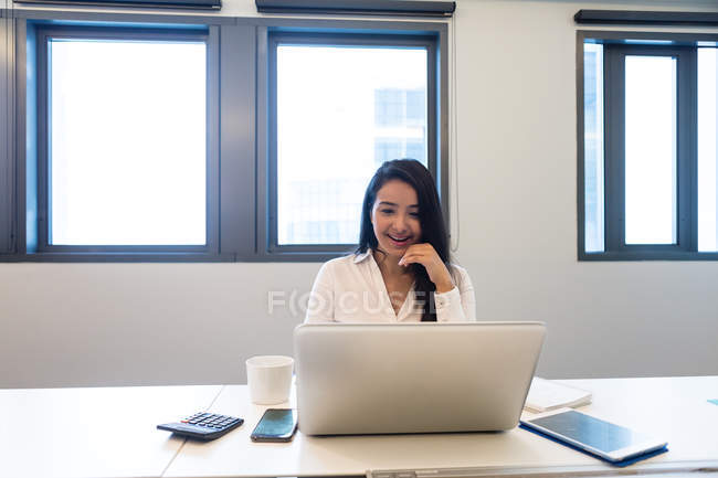 Jeune femme travaillant sur son ordinateur portable dans un bureau moderne — Photo de stock