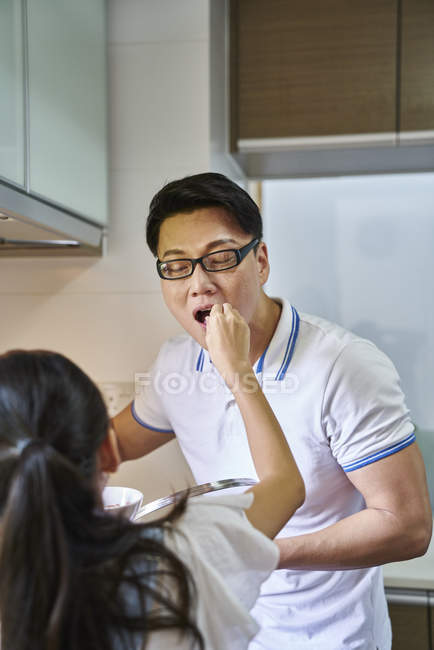 Маленька дівчинка годує батька на кухні — стокове фото