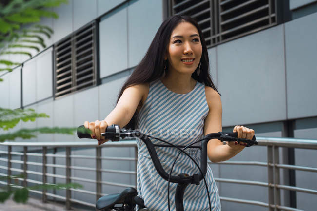 Joven asiático mujer equitación bicicleta en calle - foto de stock