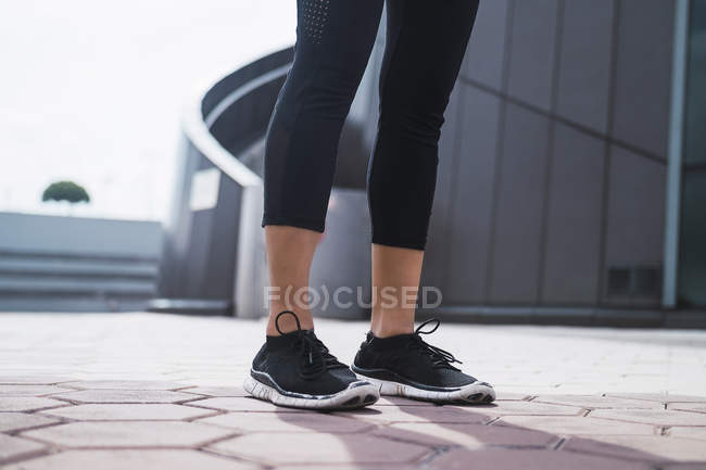 Cropped image of female legs in sneakers — Stock Photo