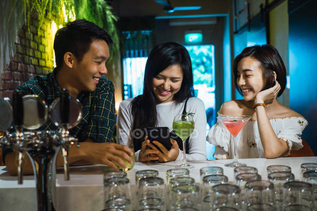 Young asian friends in comfortable bar — Stock Photo