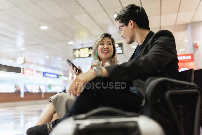 Молода пара бізнесменів з смартфон і пити в аеропорту — стокове фото