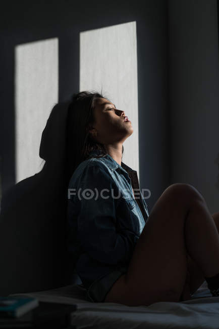 Giovane attraente asiatico donna seduta in ombre a stanza — Foto stock