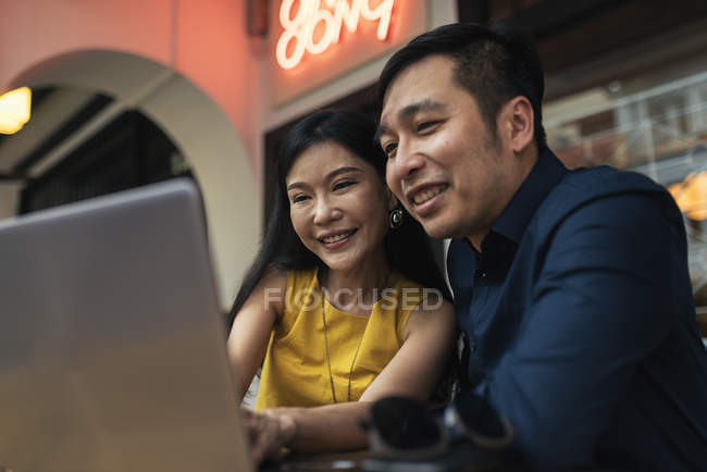 Happy young asian couple using laptop together — Stock Photo