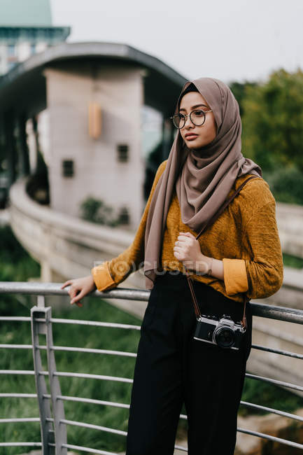Молода азіатська мусульманка в хіджабі позує біля паркану — стокове фото