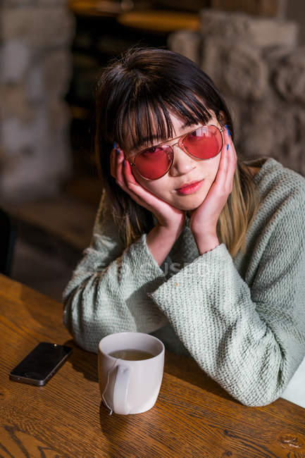 Joven adulto asiático mujer en gafas de sol con café taza - foto de stock