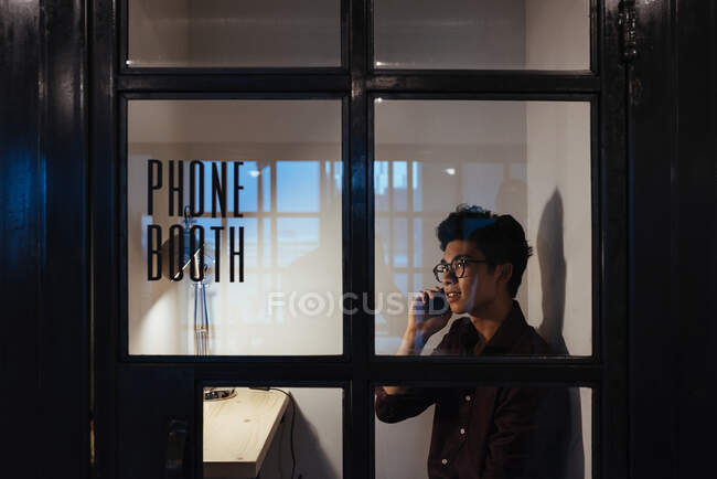 Азіат з окулярами розмовляє по мобільному телефону. — стокове фото