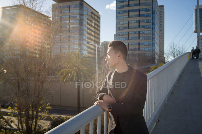 Joven asiático hombre buscando fuera en ciudad - foto de stock
