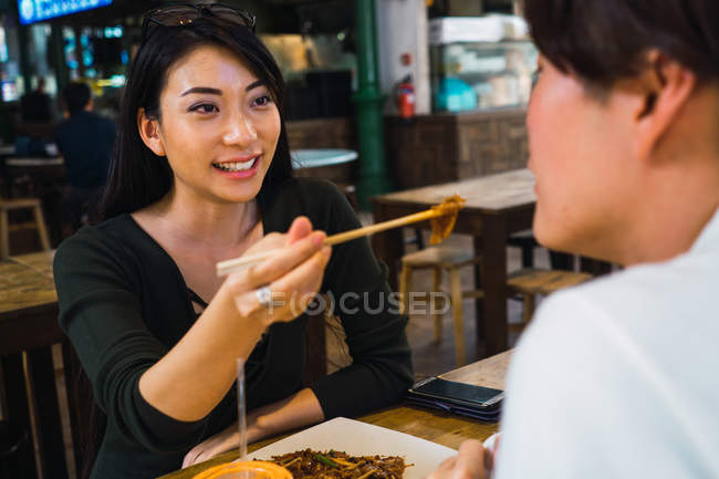 Jovem asiático casal partilha de alimentos no rua café — Fotografia de Stock