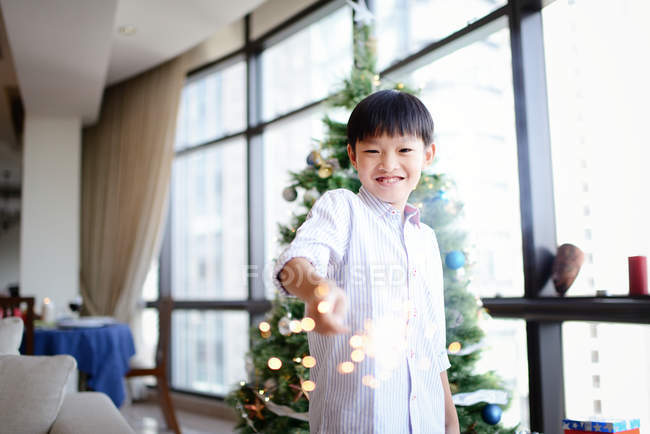 Щасливий азіатський хлопчик тримає феєрверк іскриста — стокове фото
