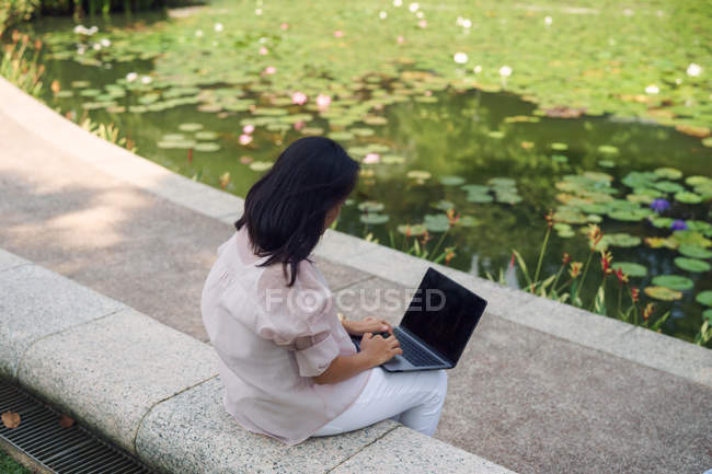 Erwachsene Frau benutzt Laptop im Park — Stockfoto