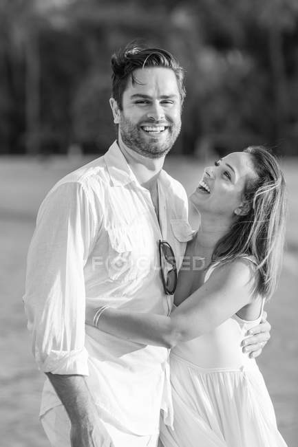 Feliz pareja caucásica abrazándose en la playa, monocromo - foto de stock
