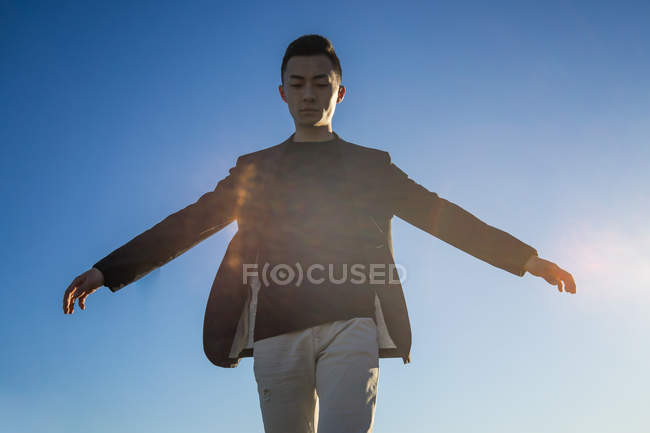 Young asian man against blue sky — Stock Photo