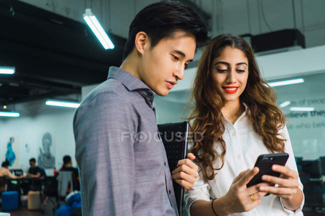 Jeunes gens d'affaires asiatiques utilisant un smartphone dans un bureau moderne — Photo de stock
