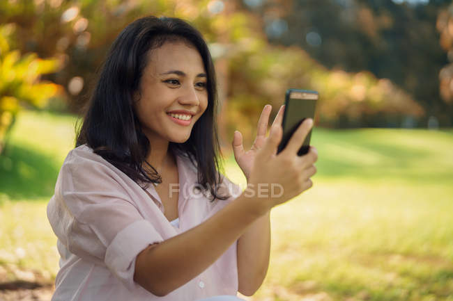 Feliz asiático mujer tomando selfie en parque - foto de stock