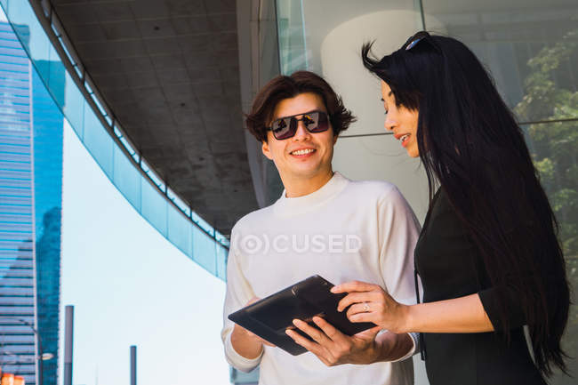 Young asian couple sharing tablet on street — Stock Photo