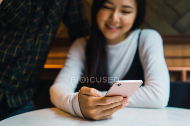 Молода азіатська жінка використовує смартфон, вибірковий фокус — стокове фото