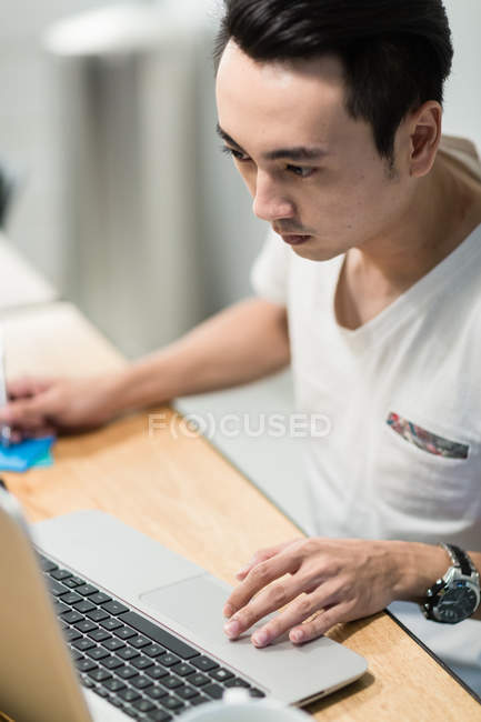 Jeune homme utilisant un ordinateur portable dans un environnement de démarrage . — Photo de stock