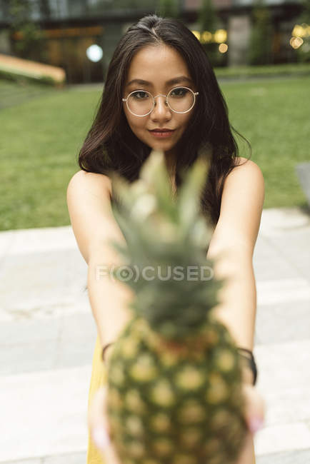 Mulher chinesa mostrando abacaxi para câmera — Fotografia de Stock