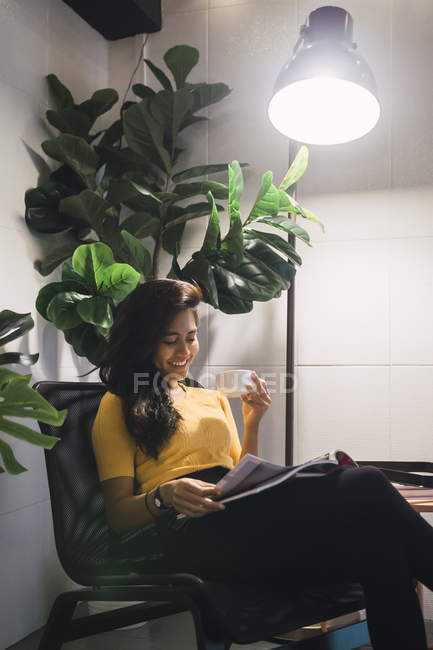 Junge asiatische Frau liest Magazin im kreativen modernen Büro — Stockfoto