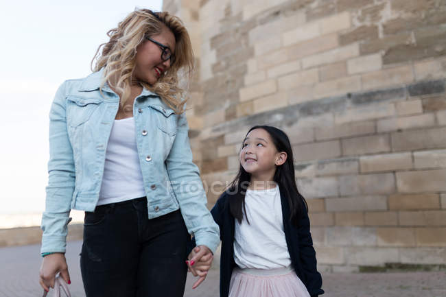 Happy young mother with her daughter walking in the city — Stock Photo