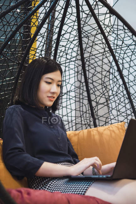 Молода азіатська жінка використовує ноутбук у творчому сучасному офісі — стокове фото