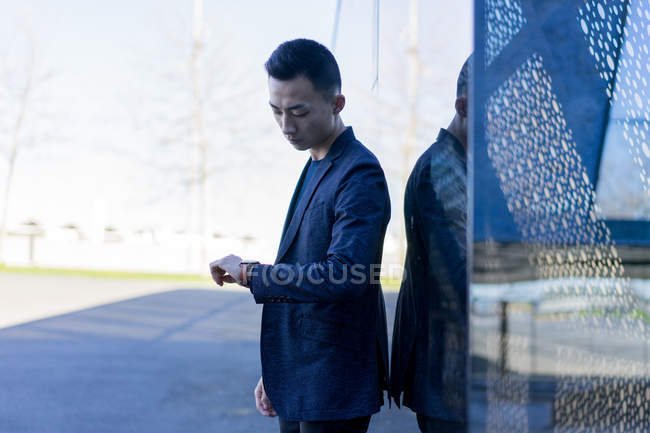 Молодий азіатський чоловік перевіряє час на міській вулиці — стокове фото