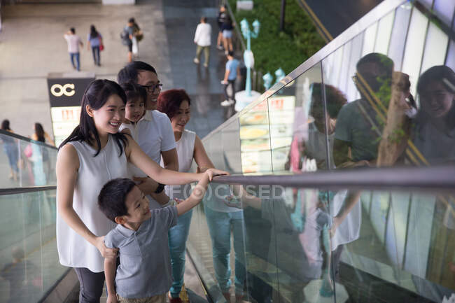 Family goes up an escalator at a shopping mall — Stock Photo