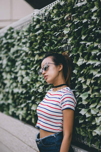 Ritratto di Giovane donna hipster in posa vicino al cespuglio — Foto stock