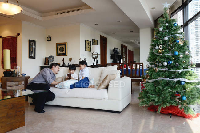 Feliz joven asiático padre y los hijos celebrando la Navidad en casa - foto de stock