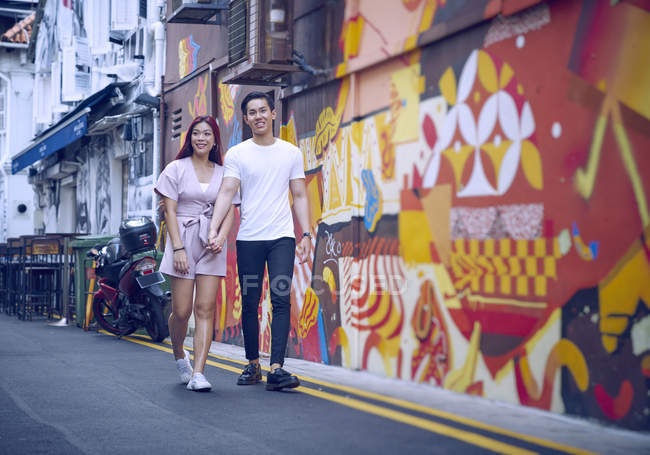 Молодая привлекательная азиатская пара обнимается и ходит по улице — стоковое фото