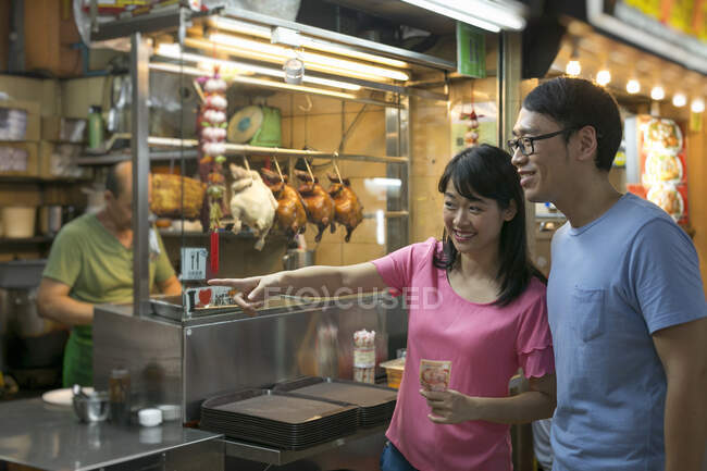 Happy asian couple in chinatown cafe pointing on something — Stock Photo