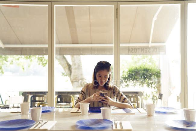 Молодая красивая азиатка, использующая смартфон в кафе — стоковое фото
