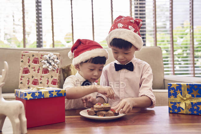 Счастливая азиатская семья празднует Рождество вместе, два мальчика с рождественским печеньем — стоковое фото