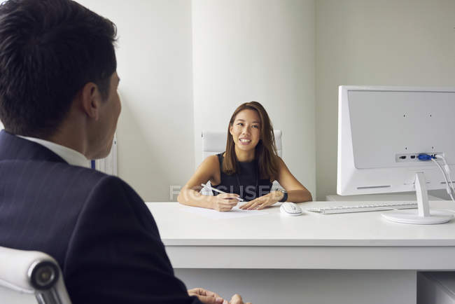 Молодая азиатская деловая женщина на встрече с мужчиной в современном офисе — стоковое фото