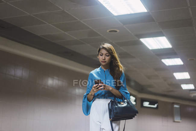 Привлекательная молодая азиатская девушка с помощью смартфона — стоковое фото