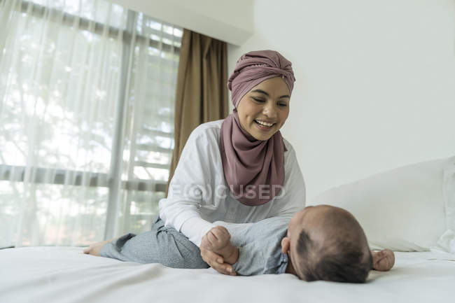 Asiático musulmán madre y bebé en casa - foto de stock