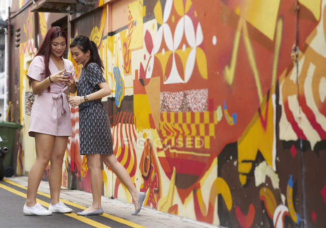 Jovem asiático amigos olhando para smartphone no rua — Fotografia de Stock