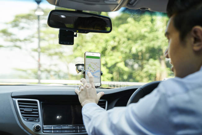 Jovem motorista do sexo masculino verificando direções em seu GPS — Fotografia de Stock
