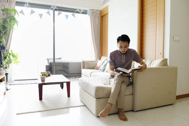 Зрілий азіатський випадковий чоловік читає книгу вдома — стокове фото