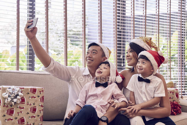 Счастливая молодая азиатская семья празднует Рождество вместе и делает селфи — стоковое фото