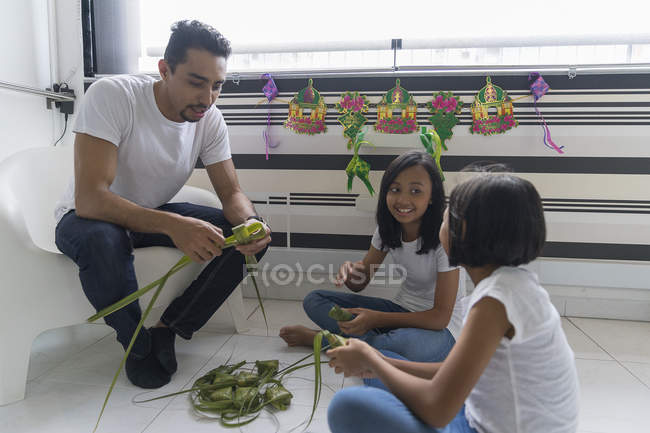 Feliz asiático familia celebrando hari raya en casa y preparando decoraciones - foto de stock