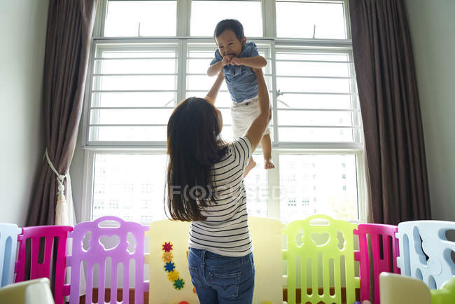 Mutter trägt ihr Kind im Spielzimmer — Stockfoto