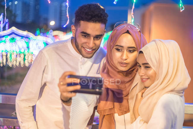 Три молодих мусульмани беруть селфі в нічний час на мосту — стокове фото