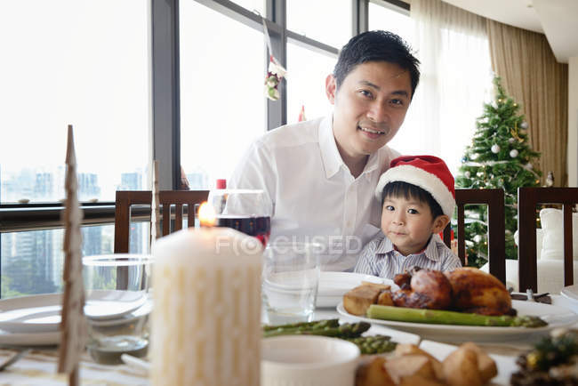 Happy asian family celebrating Christmas together at home, father with son sitting by table — Stock Photo