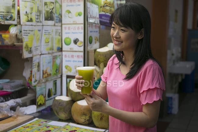 Happy asian woman with fresh juice in chinatown cafe — Stock Photo