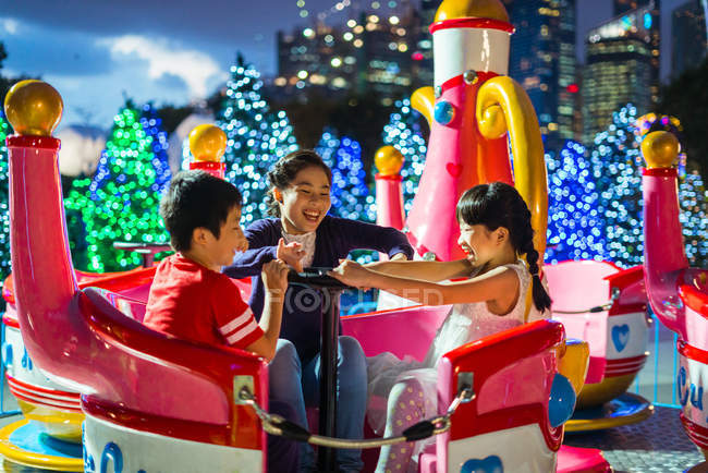Heureux asiatique frères et sœurs passer du temps ensemble dans parc d'attractions à noël — Photo de stock