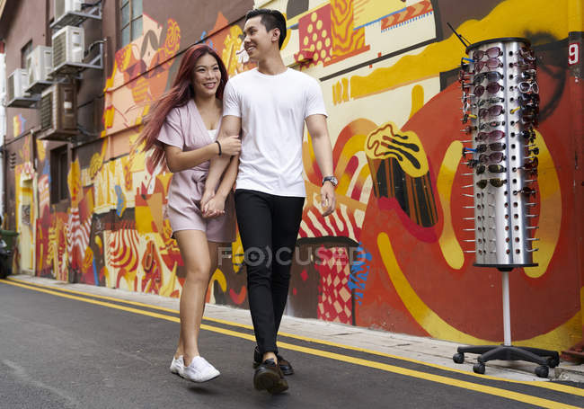 Junge attraktive asiatische Paar umarmen und zu Fuß auf der Straße — Stockfoto