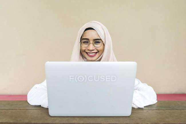 Junge asiatische muslimische Frau mit Laptop drinnen — Stockfoto